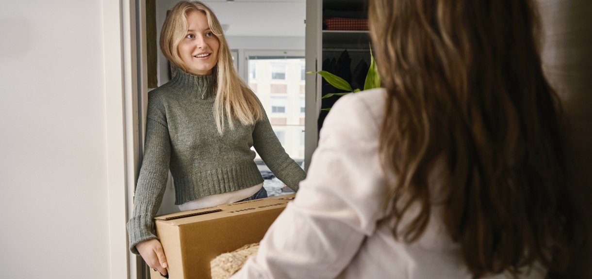 Två unga kvinnor med flyttlådor står i dörren