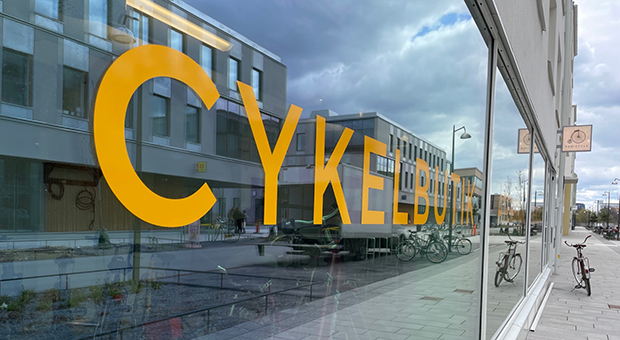 Skyltfönster med texten cykelbutik och på trottoaren står en cykel.