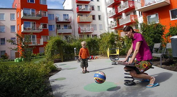 Barn leker med sin mamma på en av Svenska Bostäders lekplatser