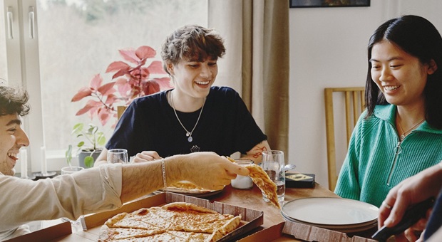 Kompisar som äter pizza vid ett bord