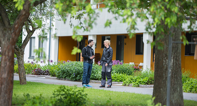 Två bovärdar pratar med varandra utanför en fastighet i Skärholmen