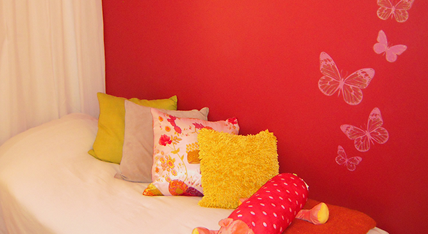 Nyrenoverat sovrum med röd vägg och fjärilmönster