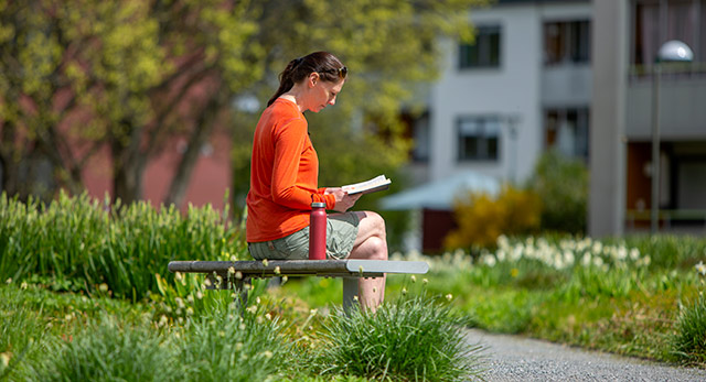 Kvinna sitter i parken och läser.