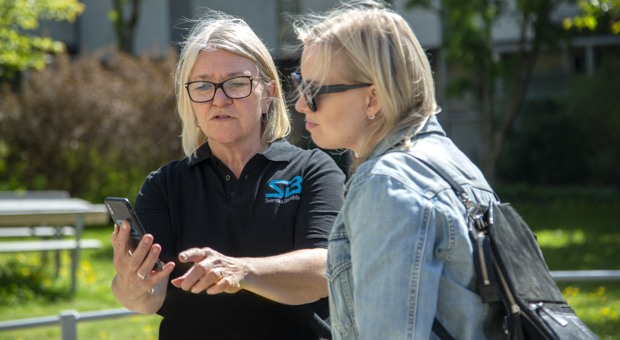 Kundvärd visar något på mobilen.