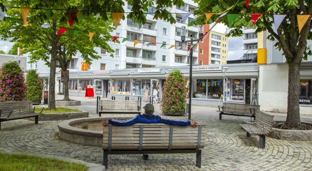 Man sitter på en bänk i Husby Centrum.