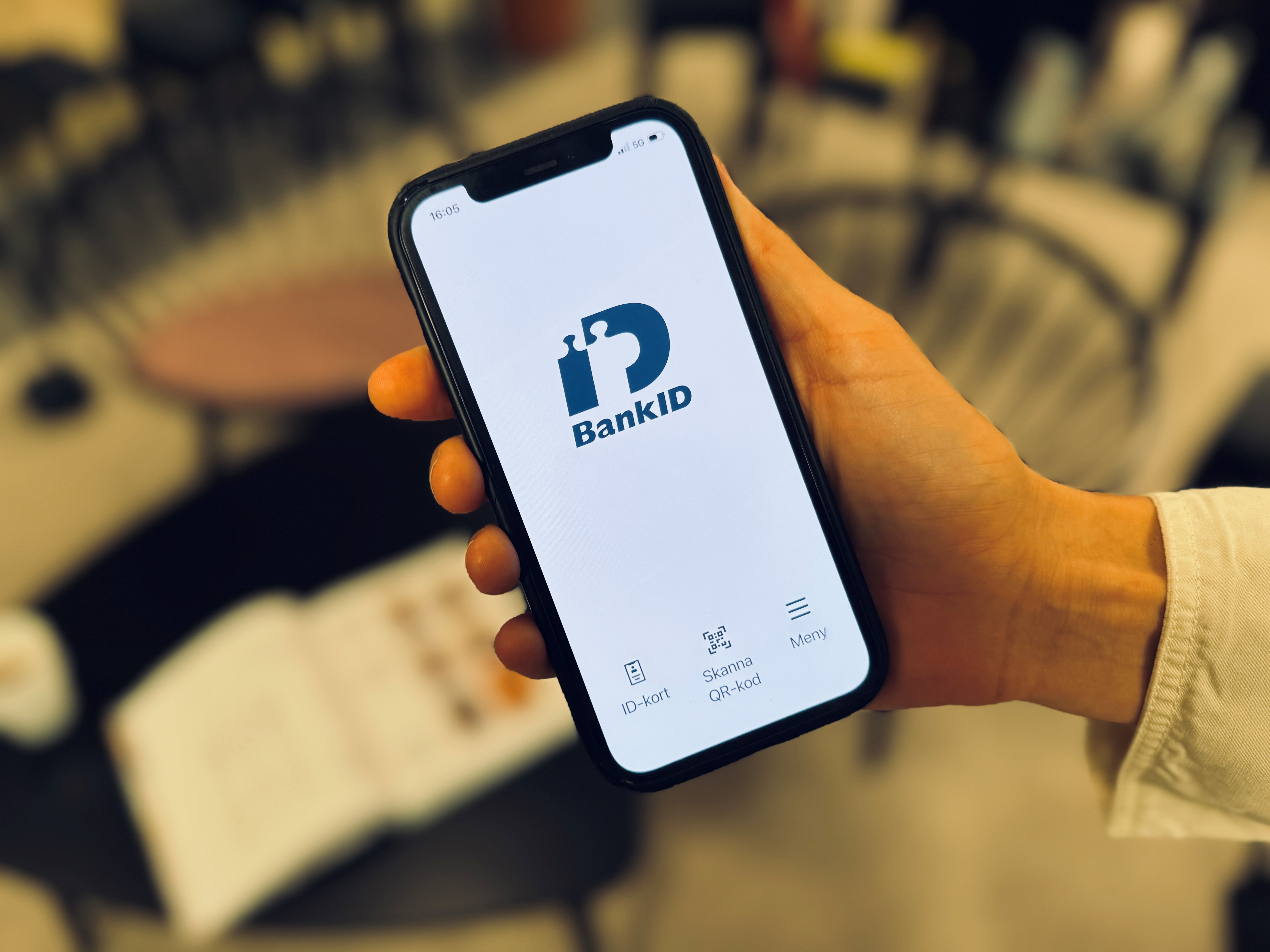 En hand som håller en mobiltelefon där appen BankID är öppen