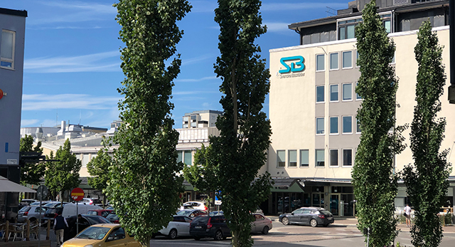 Vy över kontoret i Vällingby mellan grönklädda träd.