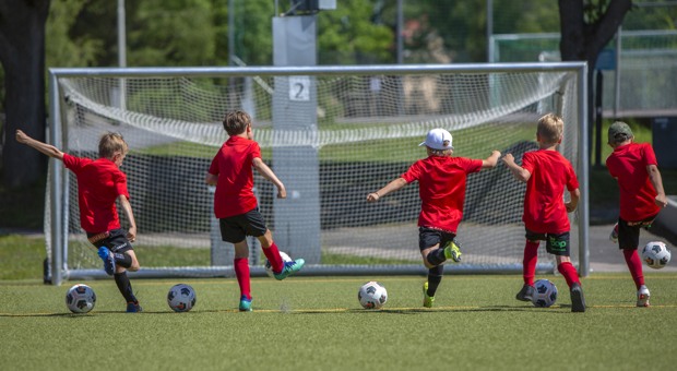 Rödklädda pojkar spelar fotboll.