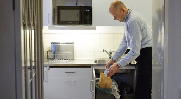 Man fyller den bruna påsen med matavfall.