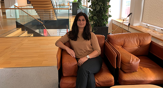 Sara klädd i brun tröja i en bruk fåtölj på huvudkontoret i Vällingby.