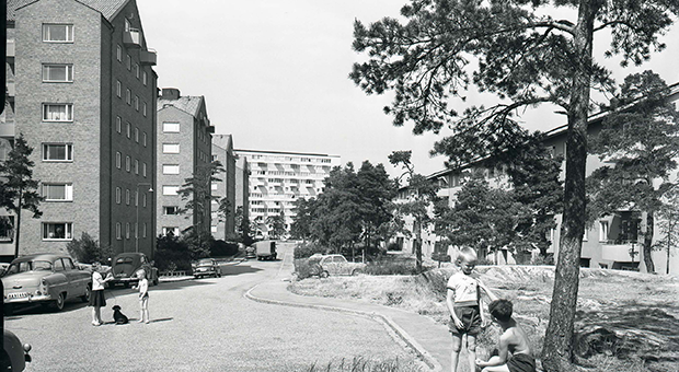 Svartvit bild på ett bostadsområde 1959. Lekande barn på gatan.